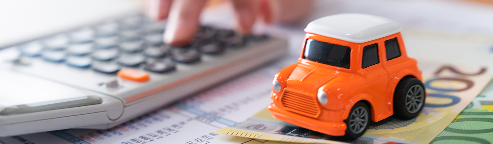 Kalkulator, model samochodu i banknoty na biurku