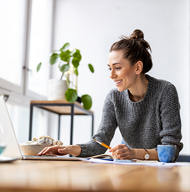 Młoda kobieta pracująca na laptopie w kawiarni