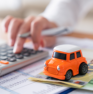 Kalkulator, model samochodu i banknoty na biurku