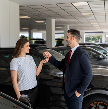Sprzedawca przekazuje kobiecie kluczyki do samochodu
